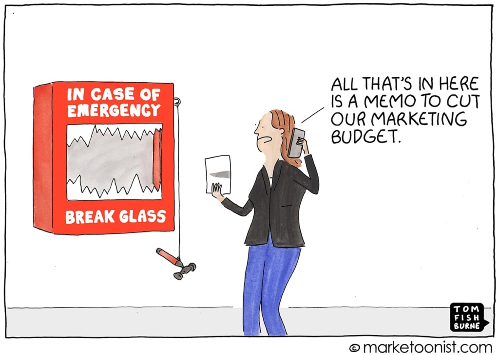 A cartoon of a marketer who is standing in front of a box that says "In case of emergency, break glass." The marketer is on the phone and says "All that's in here is a memo to cut our marketing budget."