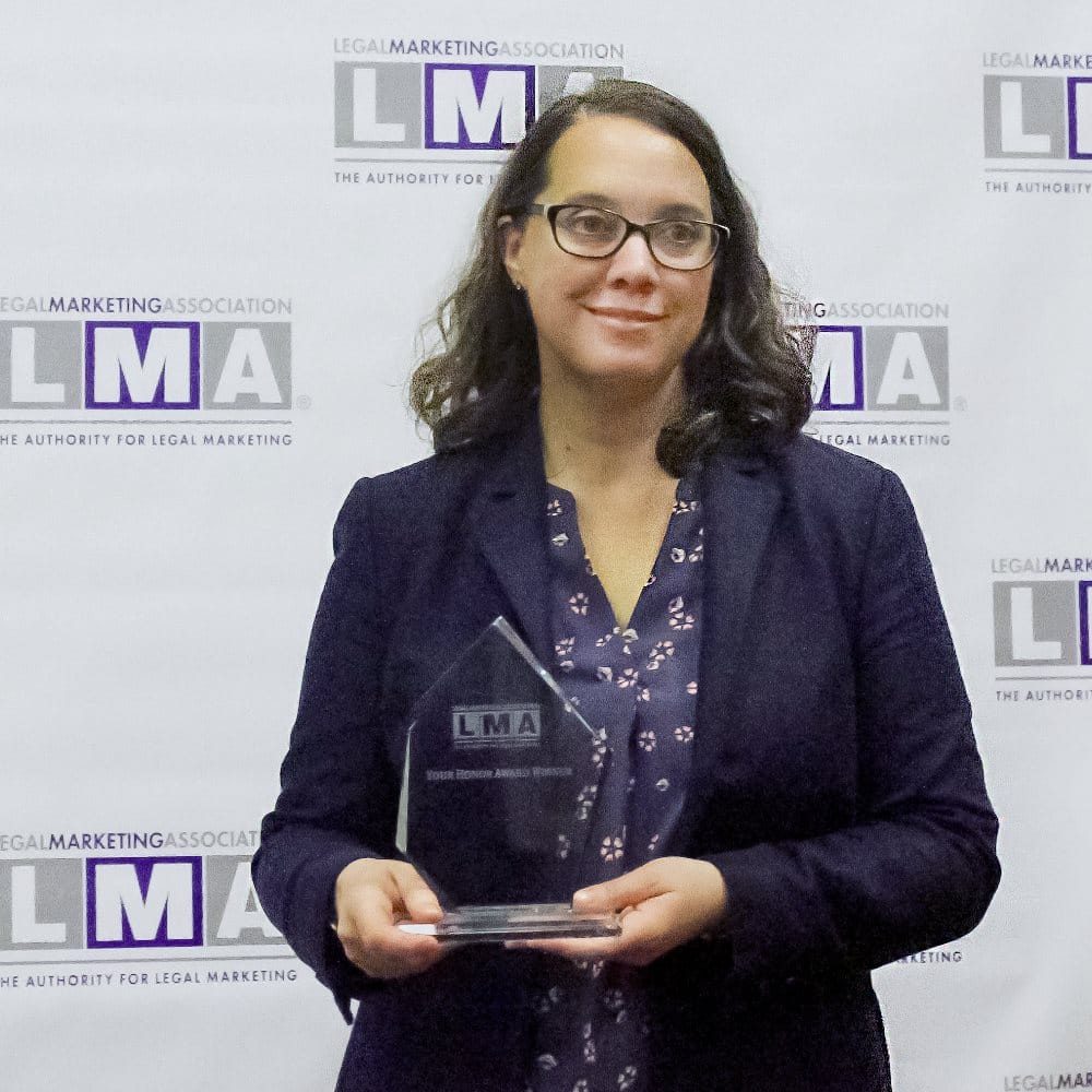 Lynn Foley, CEO of fSquared Marketing, holding the Your Honor Award for best law firm website 2018